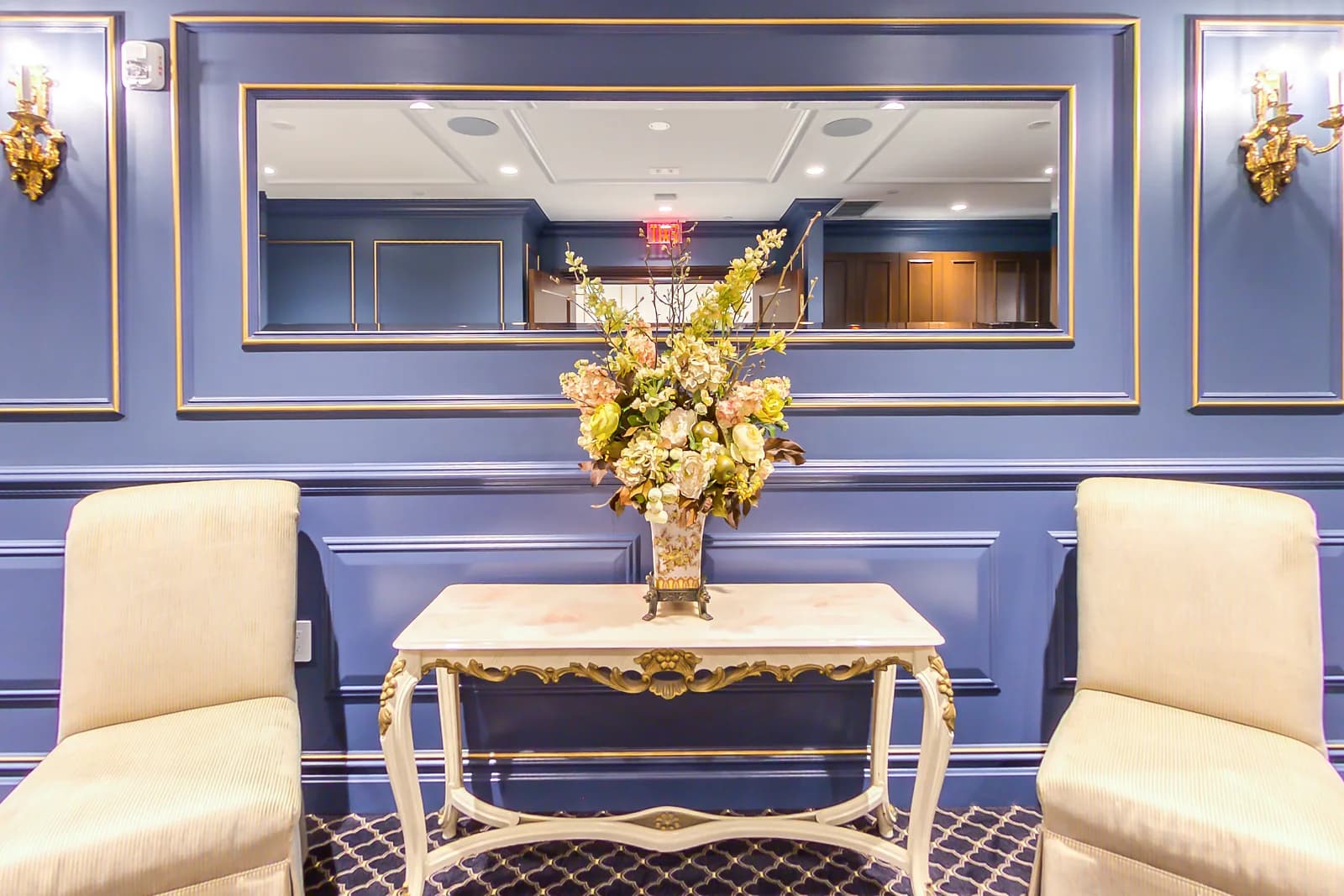 Bridal suite at Macaluso's in Hawthorne, NJ, with blue paneled walls, cream chairs and a floral console table