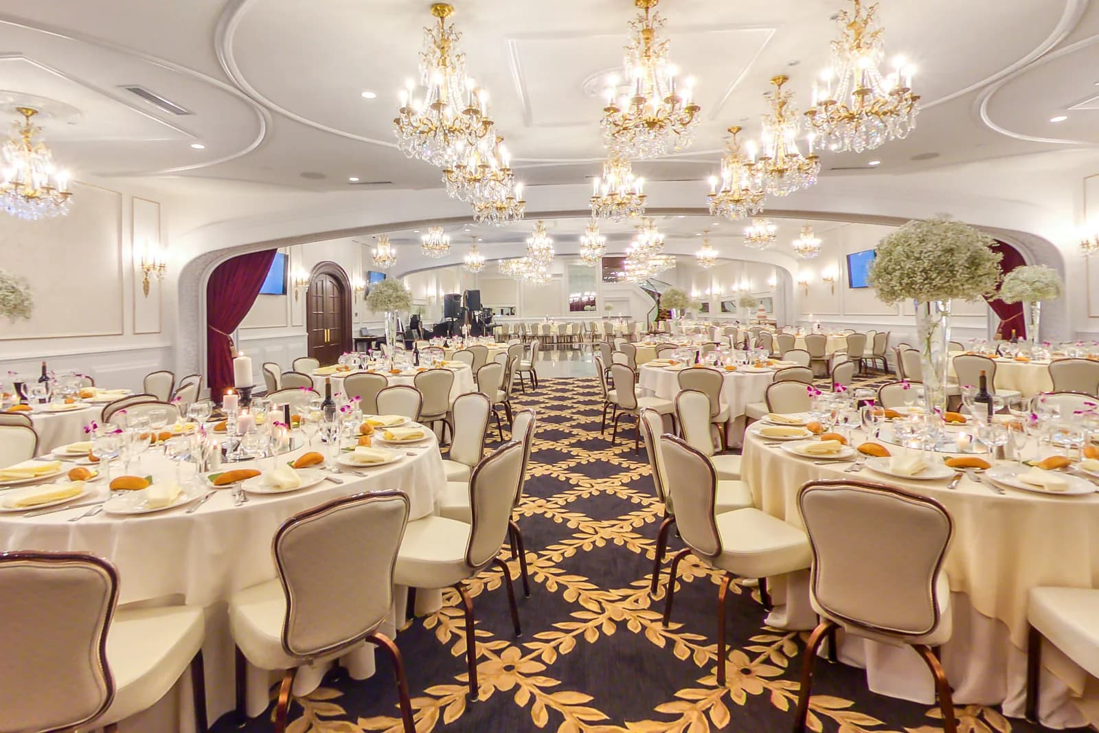 Grand Ballroom at Macaluso's in Hawthorne, NJ, with rows of crystal chandeliers, ivory-set tables and red drapes
