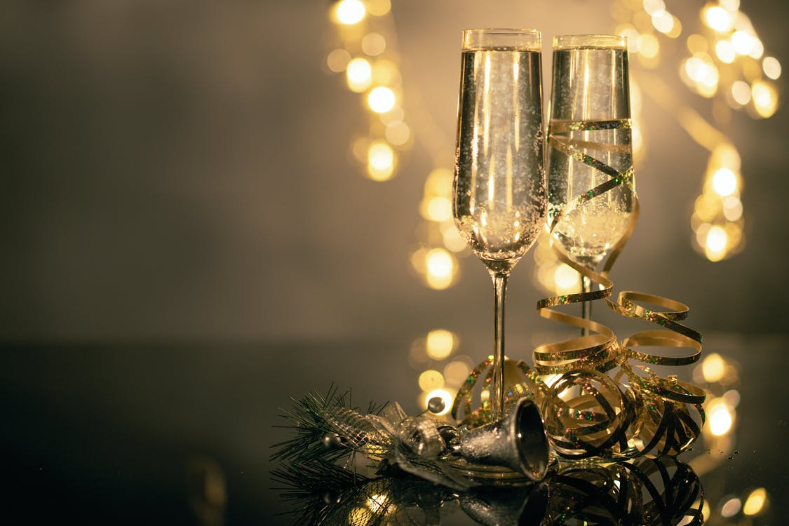Close-Up Of Two Flute Glasses Filled With Sparkling Wine Wuth Ribbons And Christmas Decor